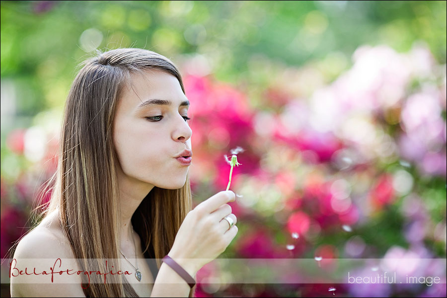 senior girl blowing on dandelion