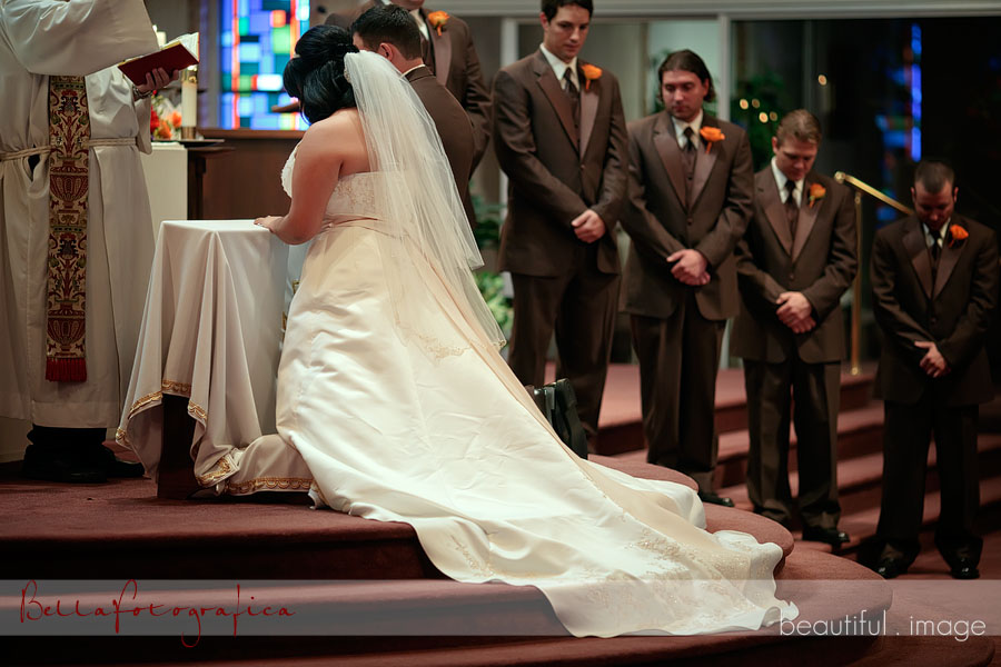 bride and groom kneeling at alter
