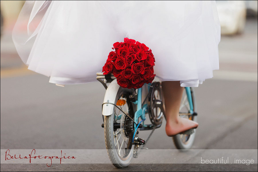 brides red rose bouquet strapped to her bike