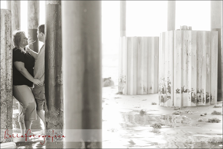 engaged couple playing under galveston pier