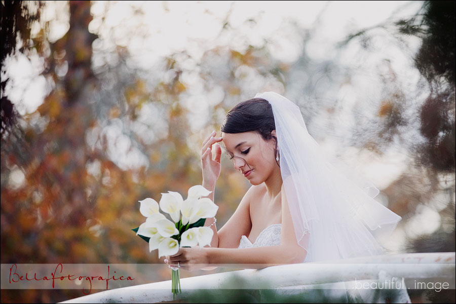 bride standing on a bridge with calla lilly bouquet adjusting her hair